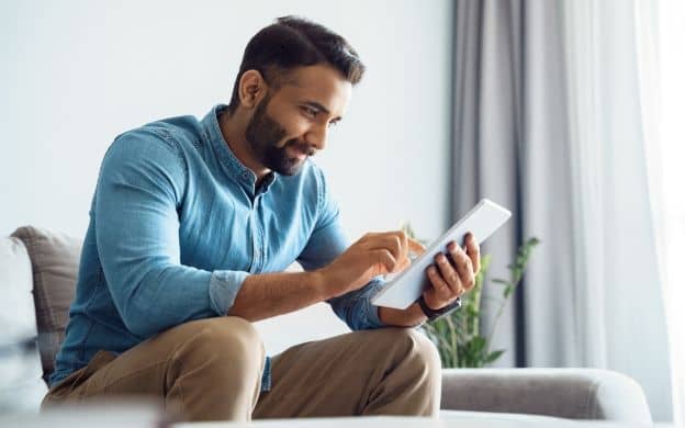 Man in light blue shirt and brown trousers using ePRO software to enter clinical trial data