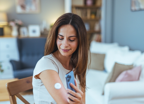 Woman holding phone to glucose monitor on her arm